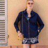 Woman in navy shirt and shorts standing against a beige wall