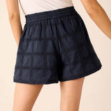 Navy blue shorts with a textured pattern worn by a person on a beige background