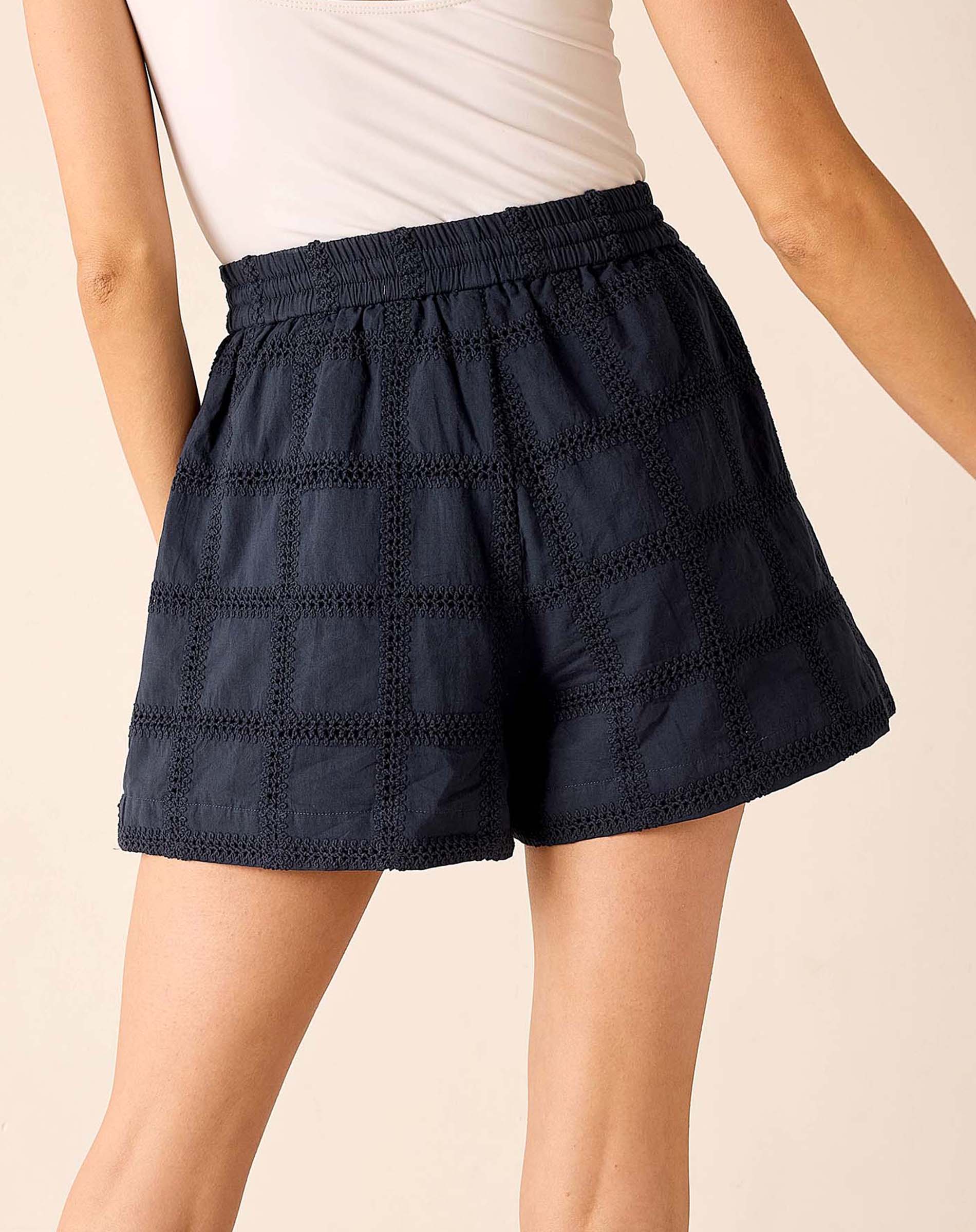 Navy blue shorts with a textured pattern worn by a person on a beige background