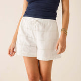 Person wearing white shorts and a navy top on a plain background