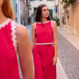 Woman in a red outfit standing on a narrow street with buildings on either side.