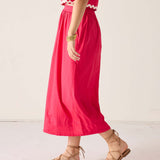 Person wearing a red dress with white trim on a light background
