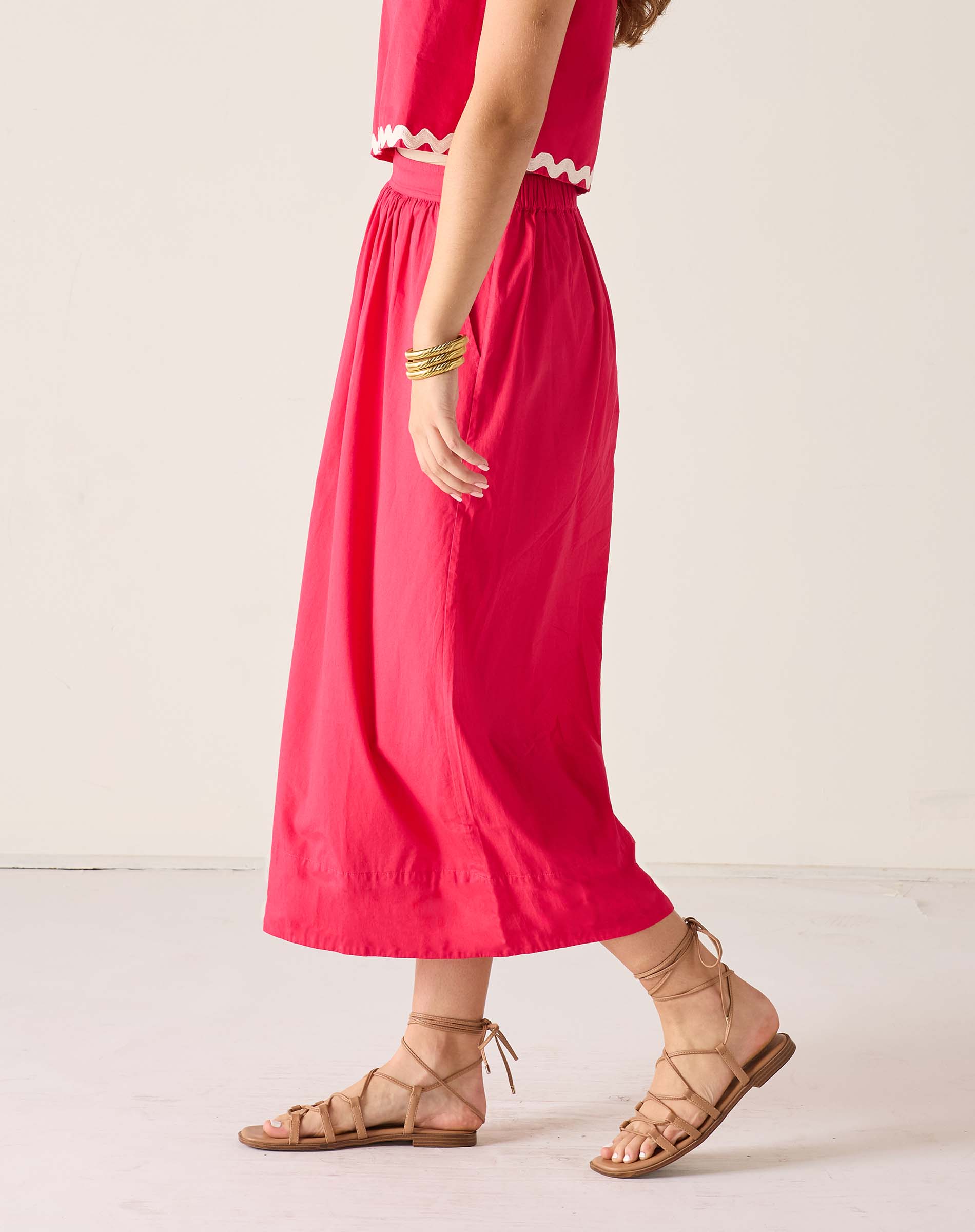 Person wearing a red dress with white trim on a light background