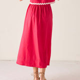 Person wearing a red dress with white trim on a light background
