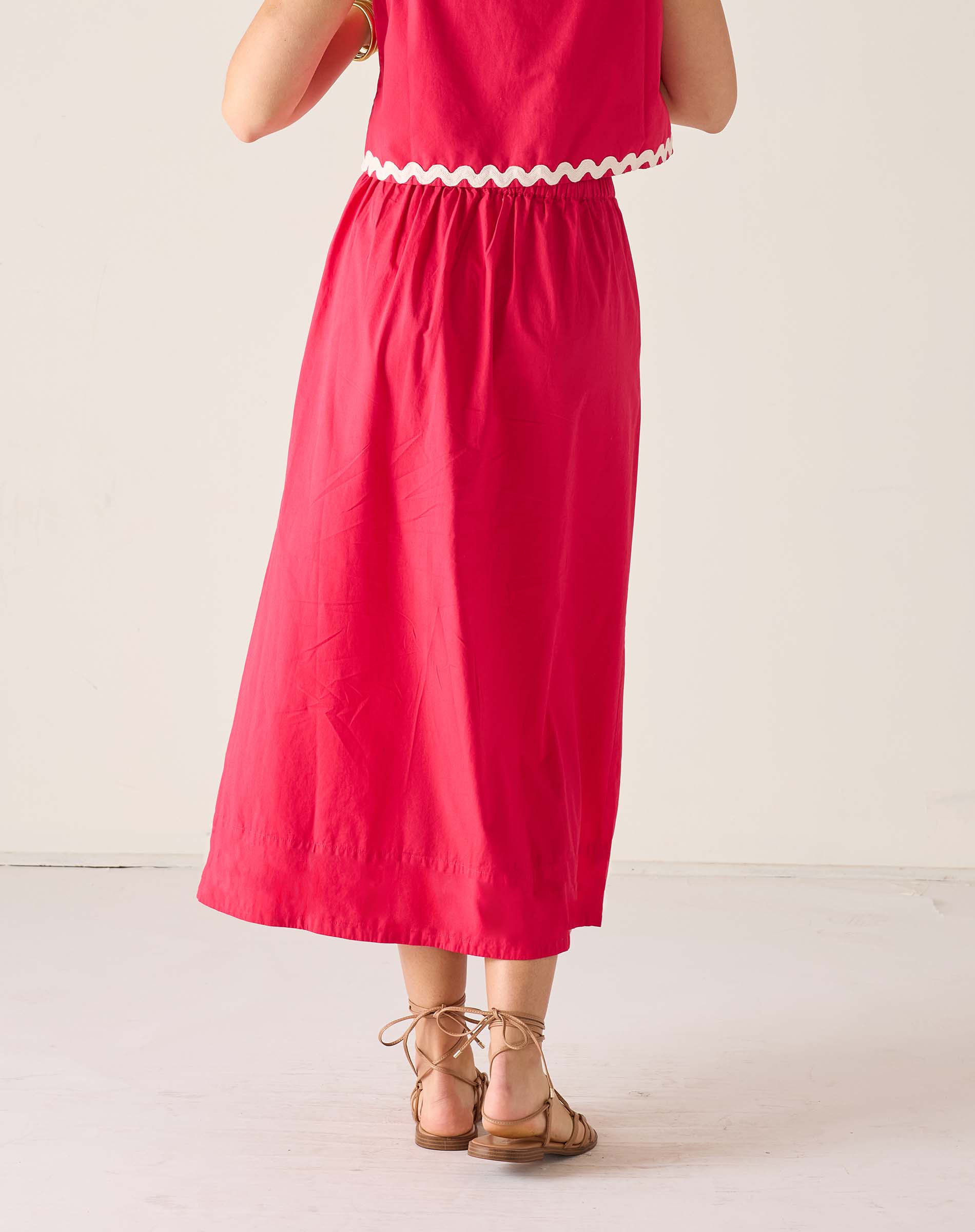 Person wearing a red dress with white trim on a light background