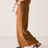 Person wearing brown wide-leg pants and black sandals on a plain background