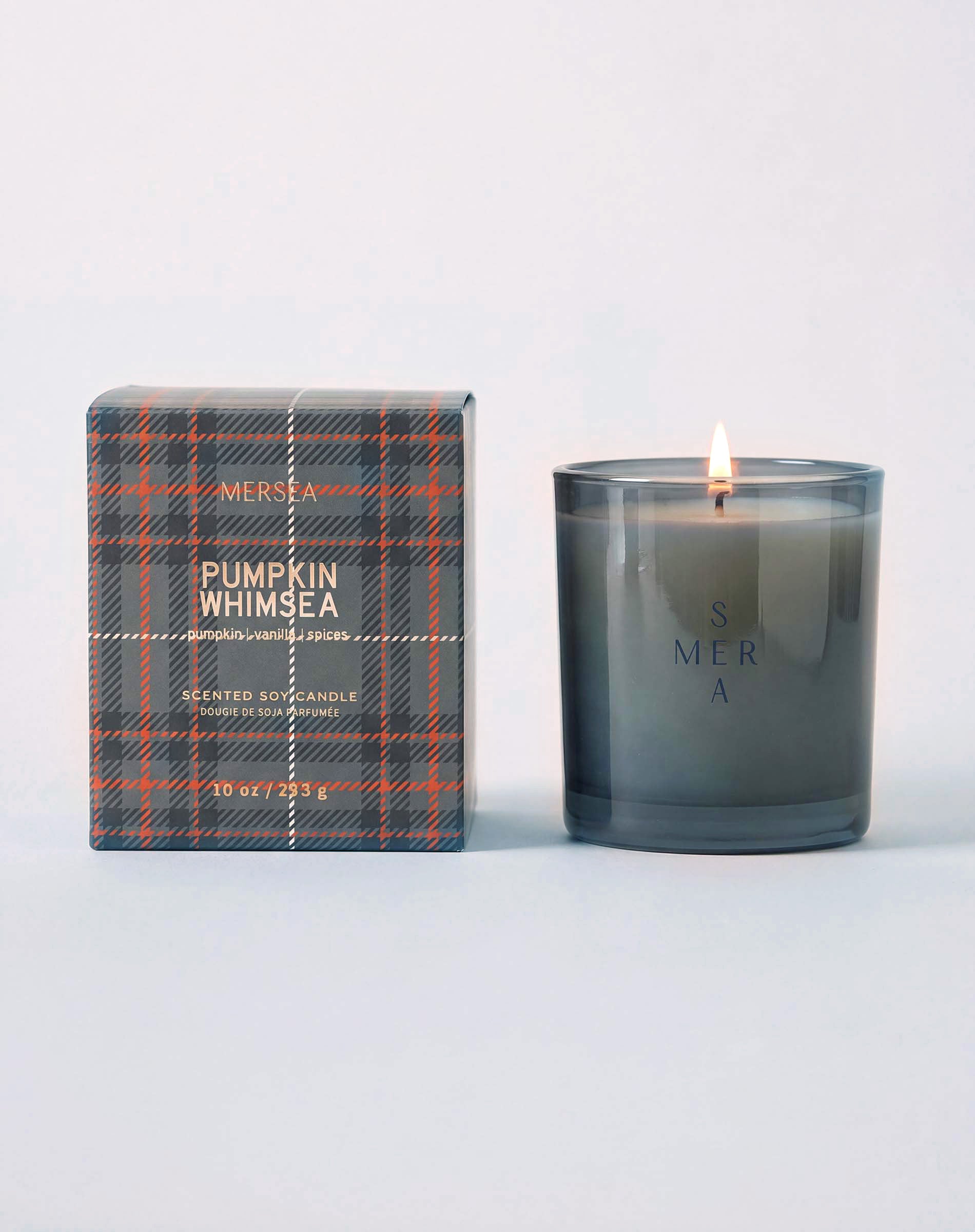 MERSEA ladies' travel-ready pumpkin Whimsea scented soy candle in a frosted glass jar with a matching plaid-patterned box. Text: 'MERSEA', 'PUMPKIN WHIMSEA', 'SCENTED SOY CANDLE', '10 oz / 283 g'
