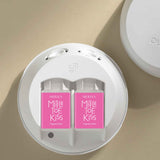 Two pink packages labeled 'Mistle Toe Kiss' in a white circular holder on a beige background.