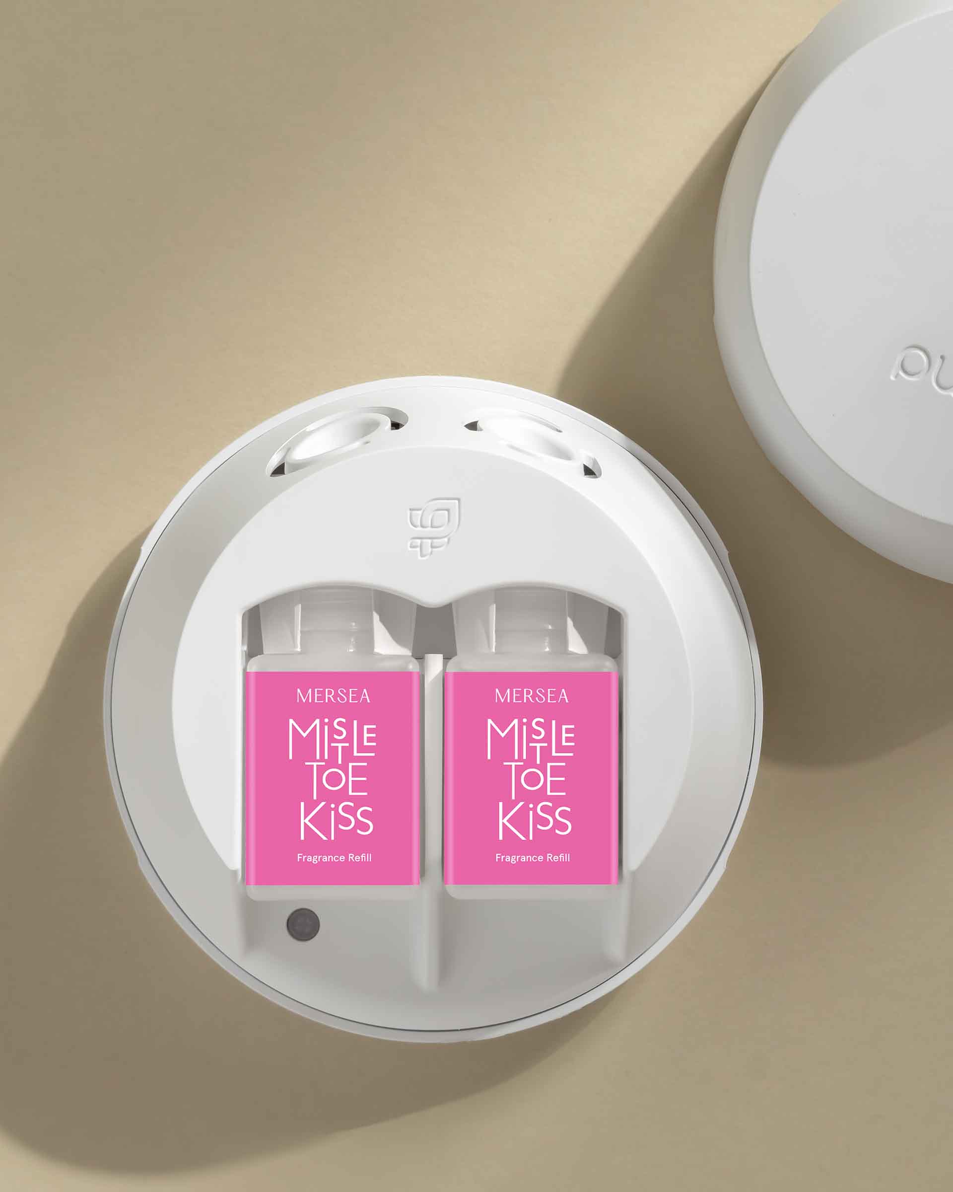 Two pink packages labeled 'Mistle Toe Kiss' in a white circular holder on a beige background.