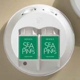 Two Mersea Sea Pines fragrance refills in a white holder on a beige background