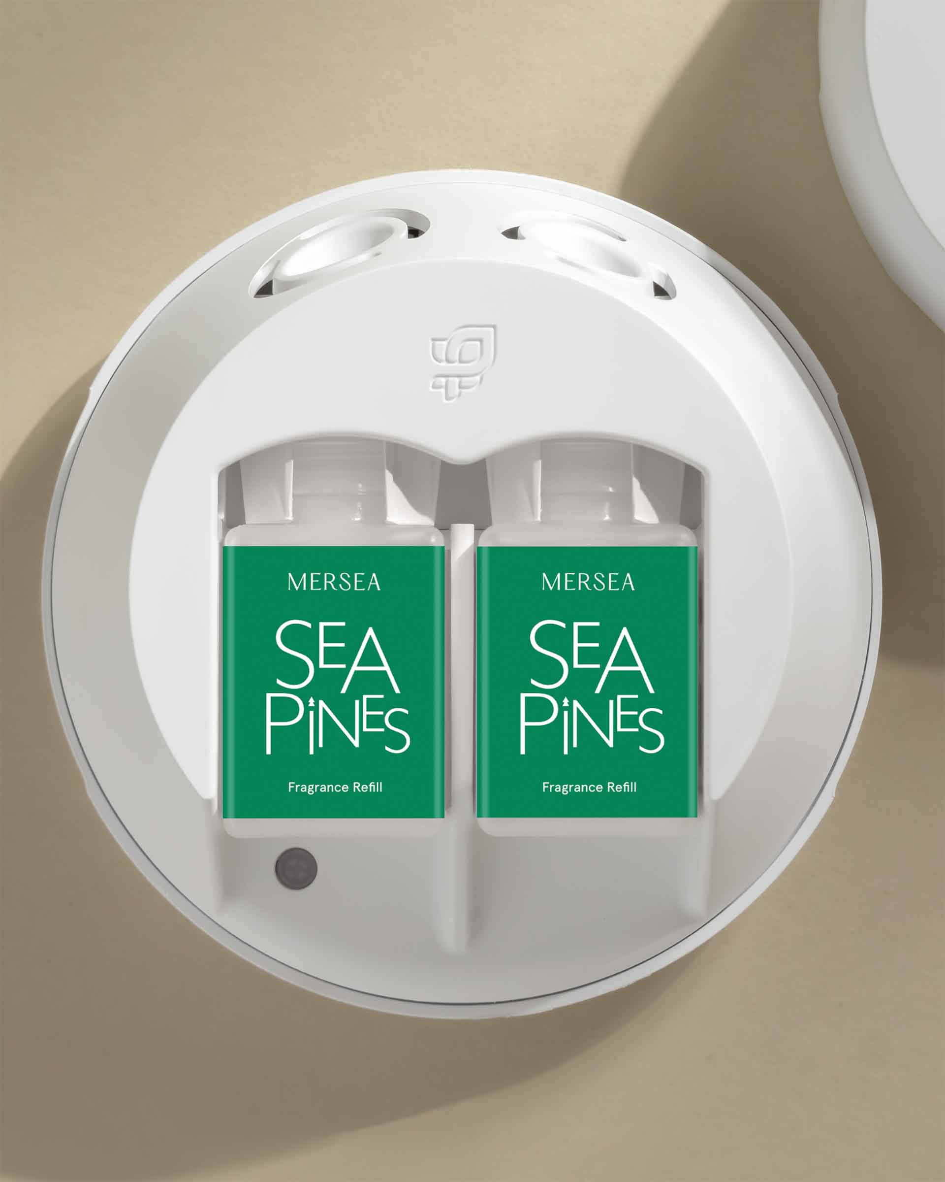 Two Mersea Sea Pines fragrance refills in a white holder on a beige background