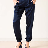 Navy blue satin jogger pants with elastic cuffs and a relaxed fit.