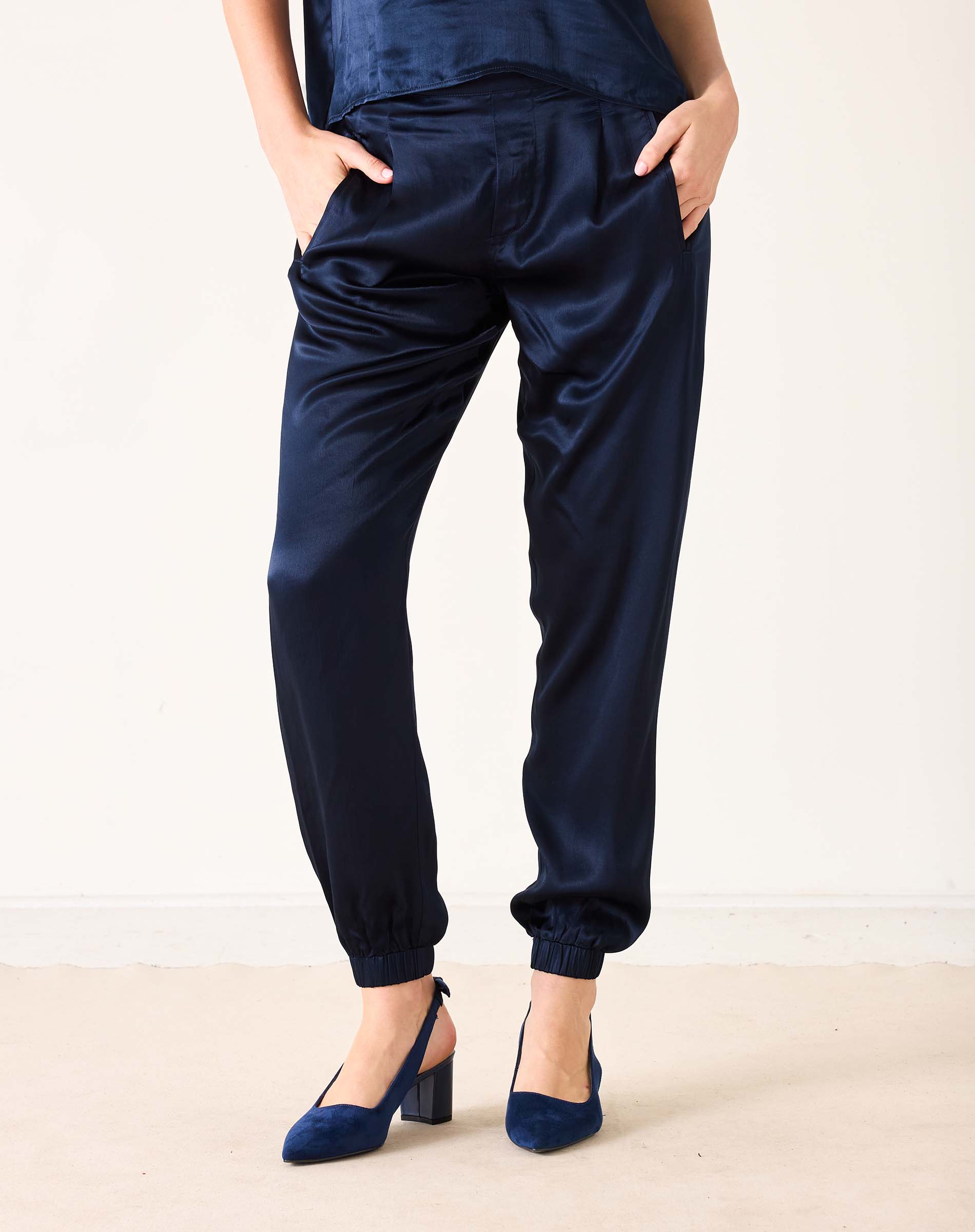 Navy blue satin jogger pants with elastic cuffs and a relaxed fit.