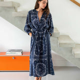 Woman wearing a blue patterned robe standing in a modern interior setting.