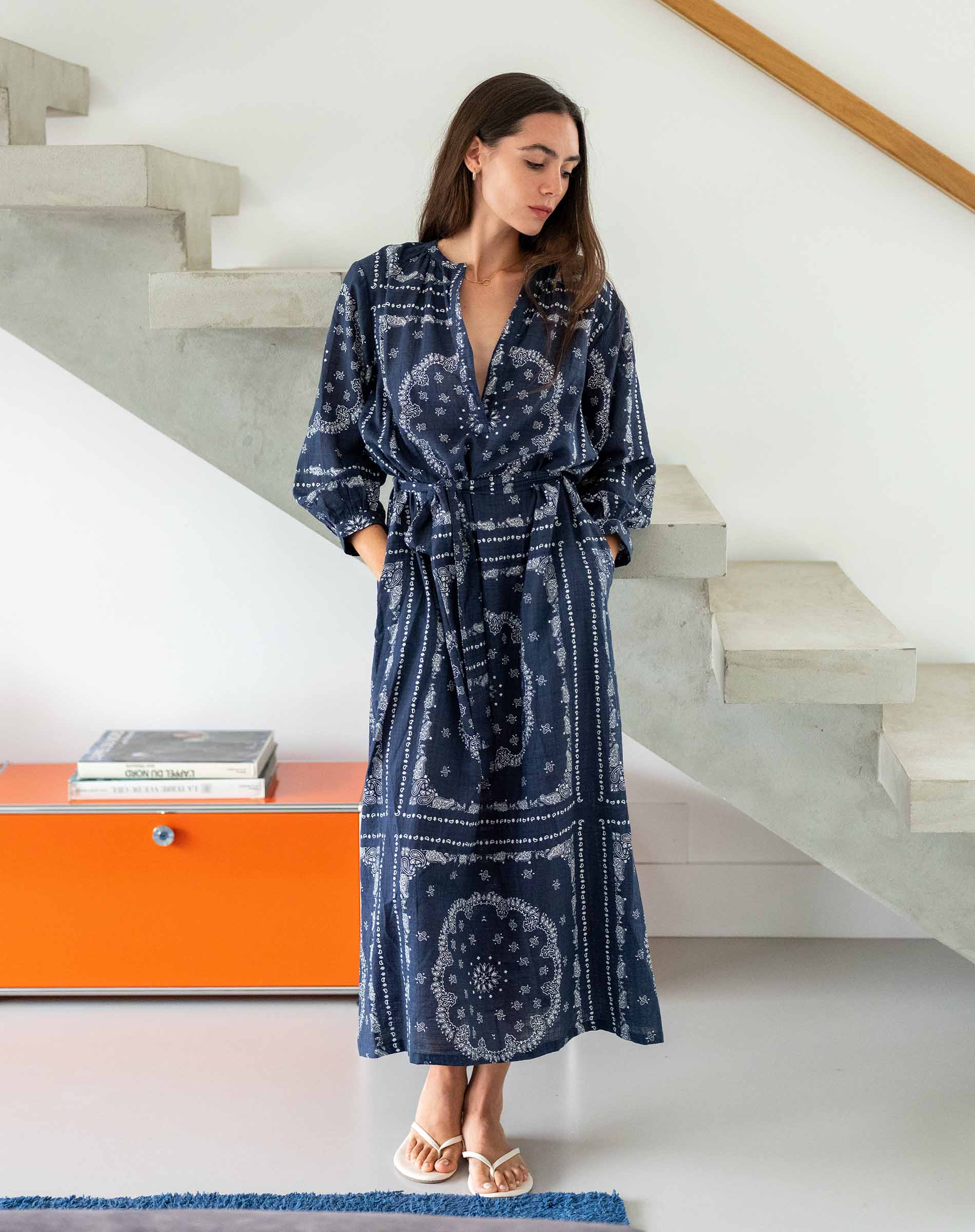Woman wearing a blue patterned robe standing in a modern interior setting.
