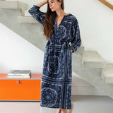 Woman wearing a blue patterned robe standing in a modern interior setting.