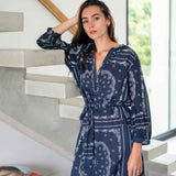 Woman wearing a blue patterned robe standing in a modern interior setting.
