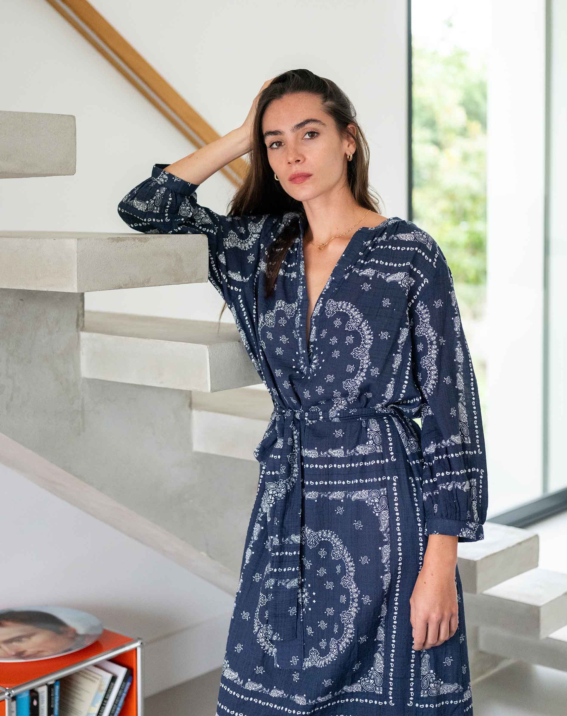 Woman wearing a blue patterned robe standing in a modern interior setting.