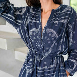 Woman wearing a navy blue dress with white patterns indoors.