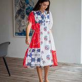 Woman wearing a colorful dress with abstract patterns in a room with a poster on the wall.
