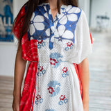 Woman wearing a floral dress with red accents in an indoor setting