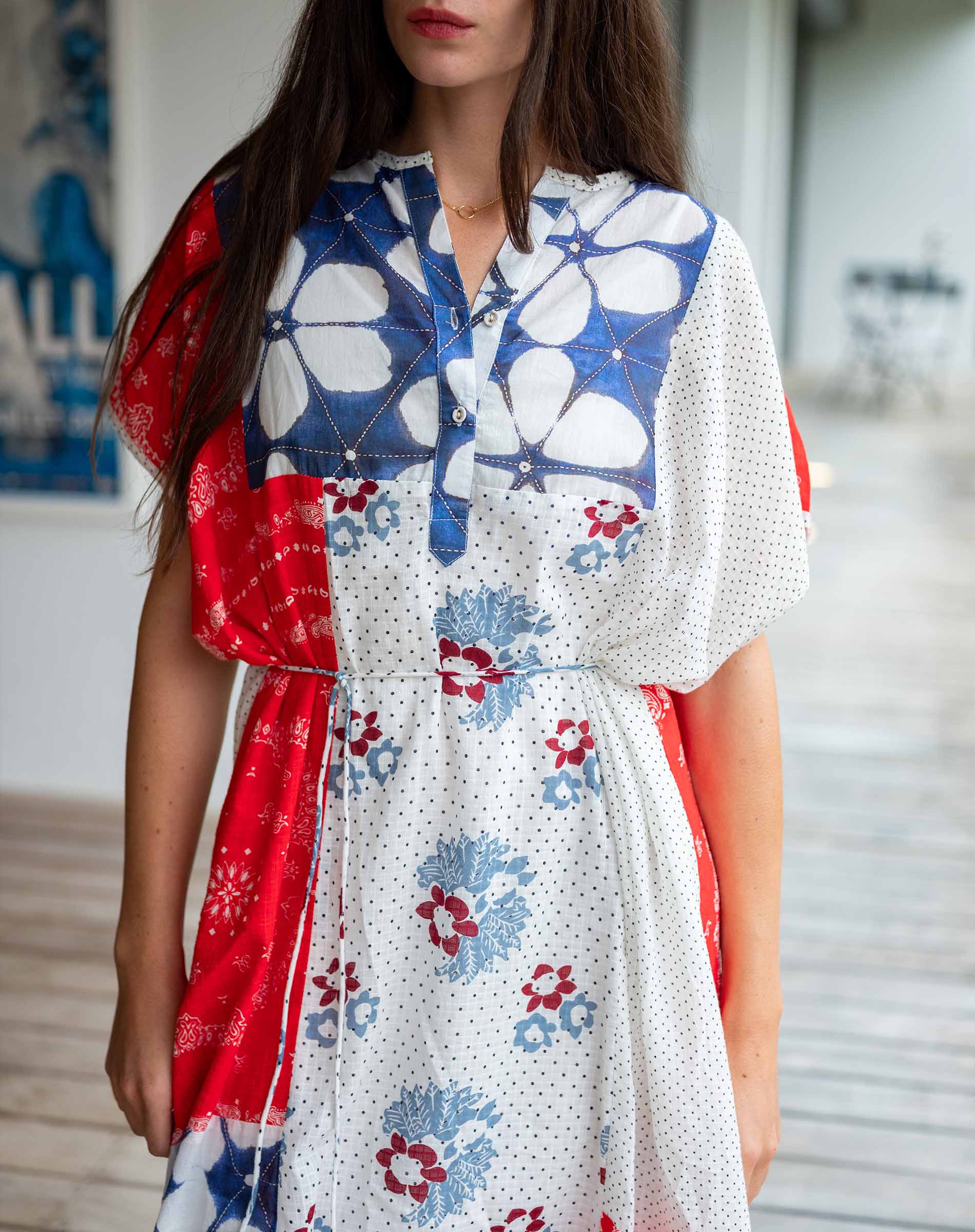 Woman wearing a floral dress with red accents in an indoor setting