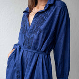 Blue dress with intricate patterns on a plain background