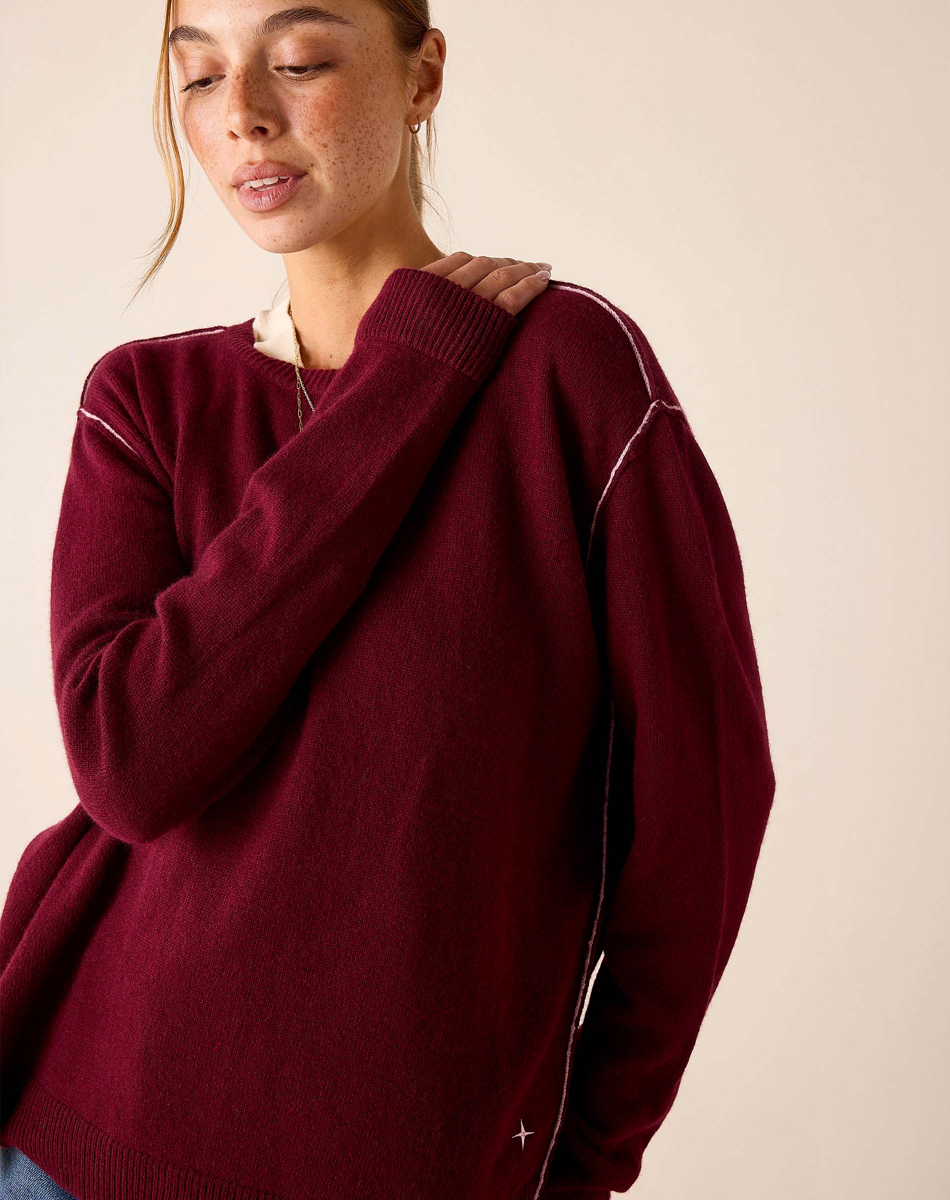 Oversized fit burgundy cashmere knit sweater with contrast stitching and ribbed cuffs.