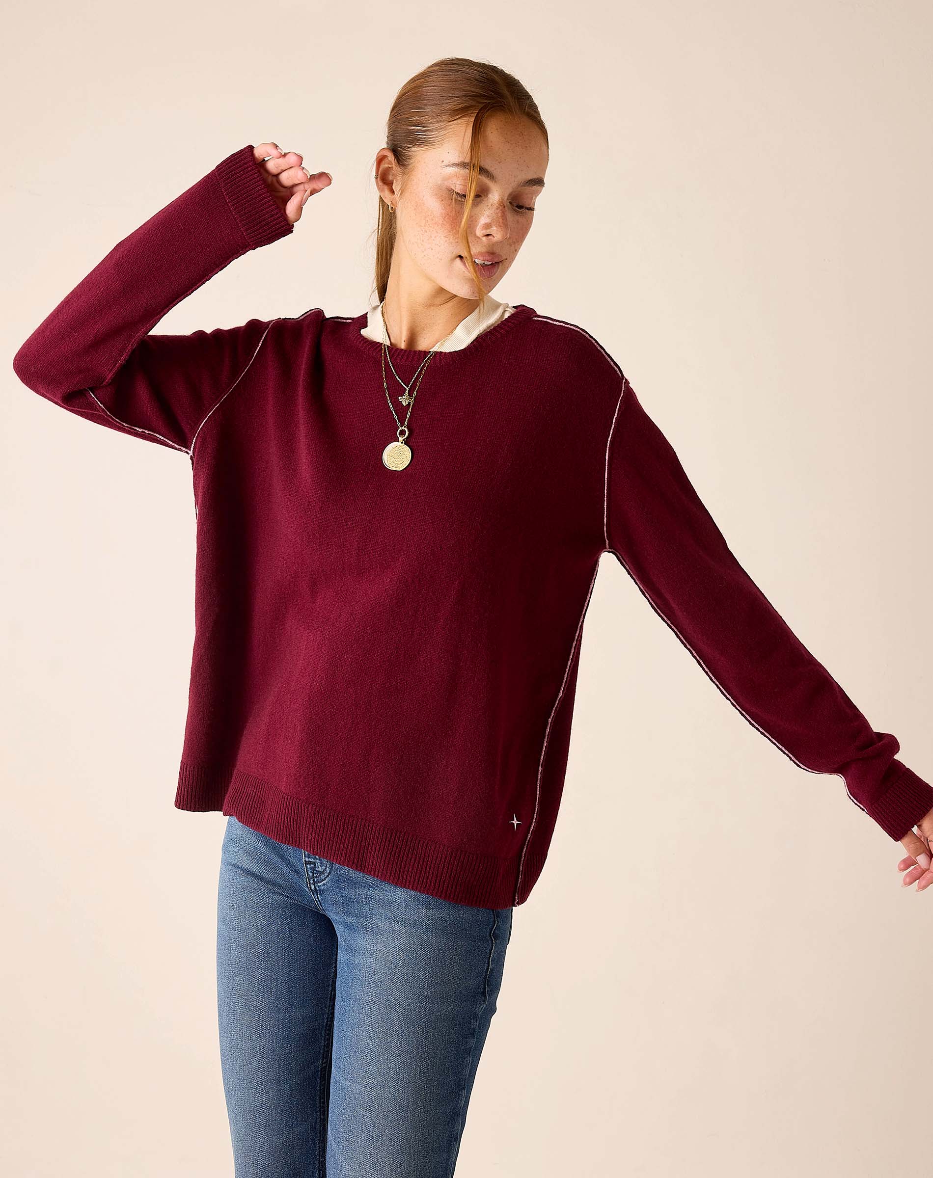 Burgundy oversized knit cashmere sweater with white contrast stitching.