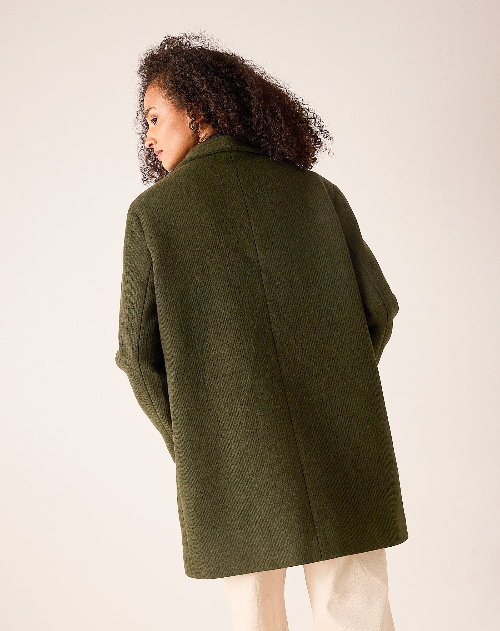 Back view of women's travel-friendly deep olive oversized textured knit jacket with wide sleeves.