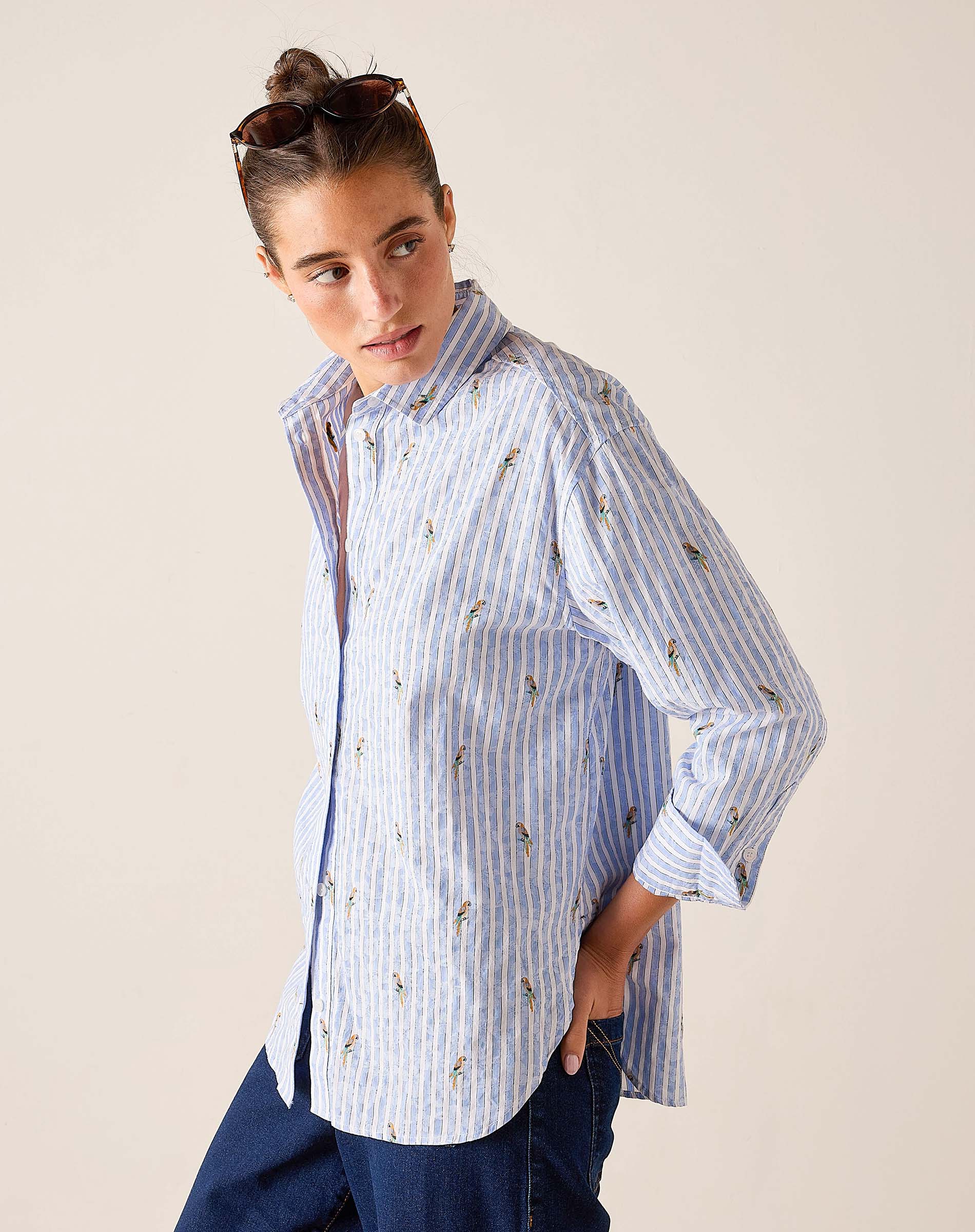 Woman wearing a blue and white striped shirt with floral patterns on a beige background