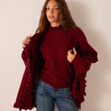 Cabernet red knit wrap with ruffled edges and wide sleeves.