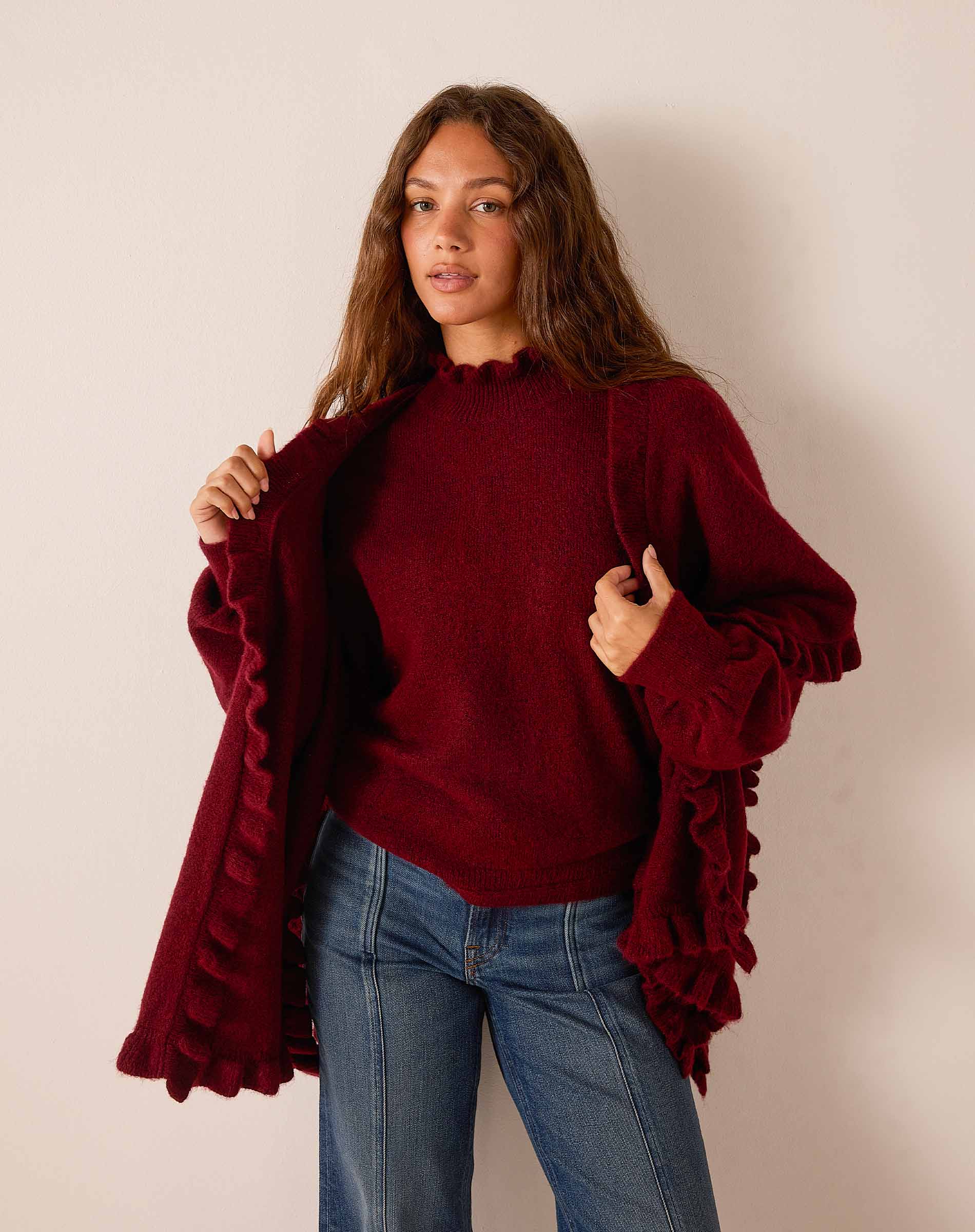Cabernet red knit wrap with ruffled edges and wide sleeves.