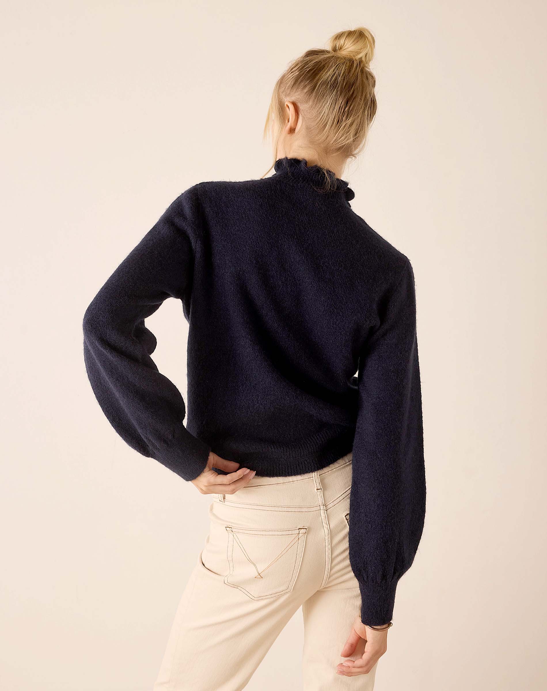Back view of the navy blue knit sweater with a high neck and gathered sleeves.