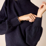 Navy blue knit sweater with a ruffled collar and voluminous lantern sleeves.