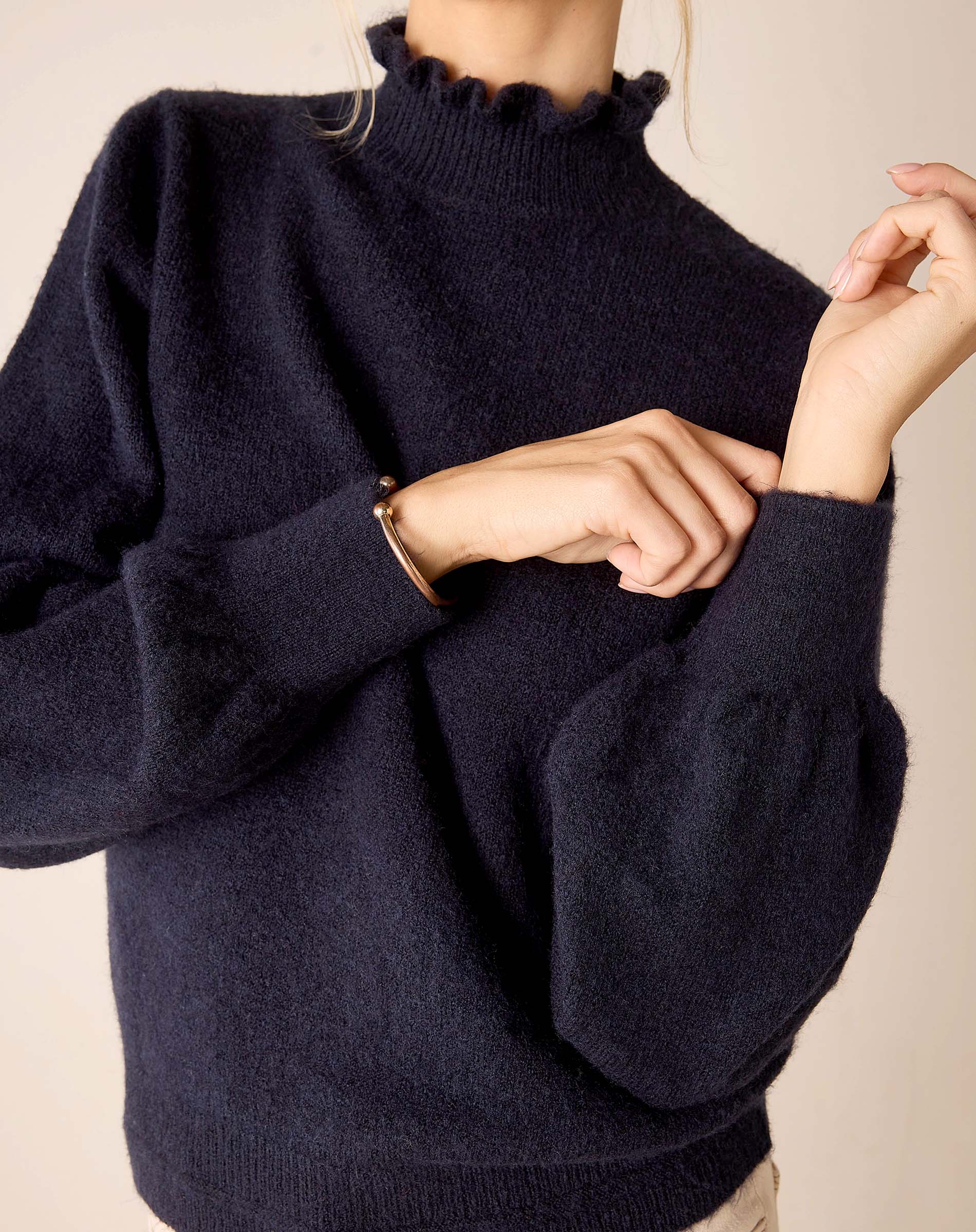 Navy blue knit sweater with a ruffled collar and voluminous lantern sleeves.