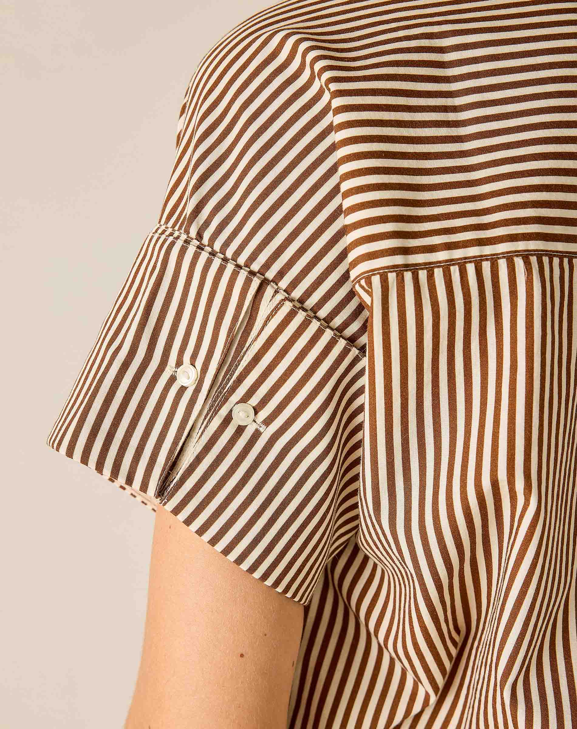 Close-up of a brown and white striped shirt with short sleeves on a beige background