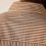 Close-up of a brown and white striped shirt with pink accents on a neutral background