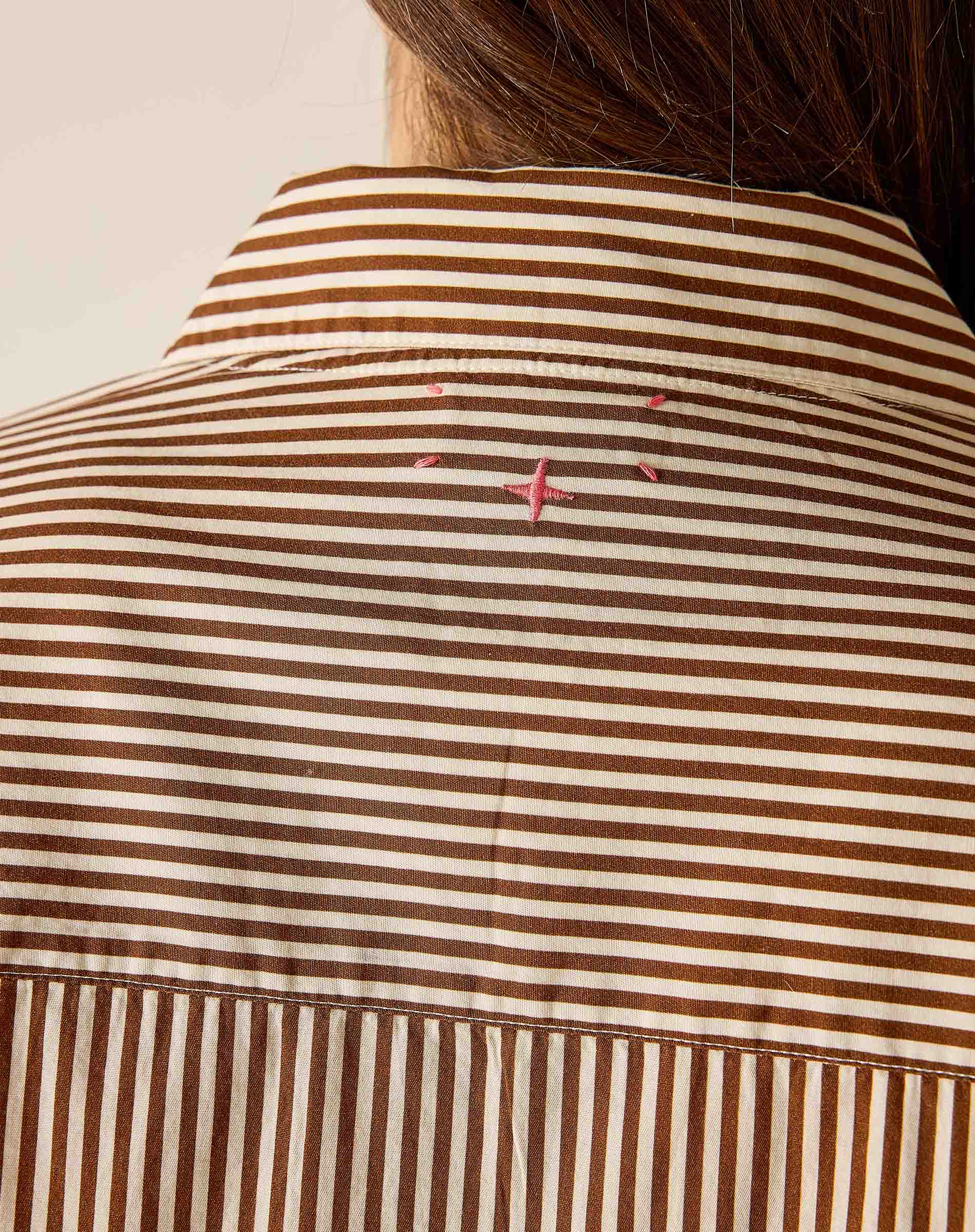 Close-up of a brown and white striped shirt with pink accents on a neutral background