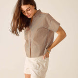 Woman wearing a striped shirt and white shorts on a plain background