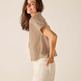 Woman wearing a striped shirt and white shorts against a plain background