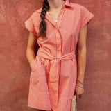 Woman wearing a red and white striped dress against a textured pink wall