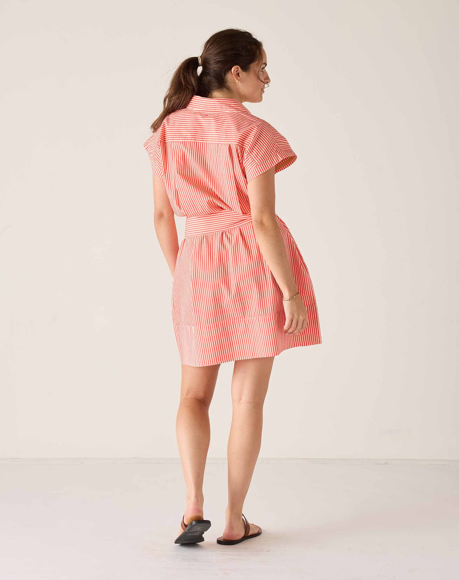 Woman wearing a red and white striped dress on a plain background