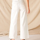 Person wearing white wide-leg pants against a beige background
