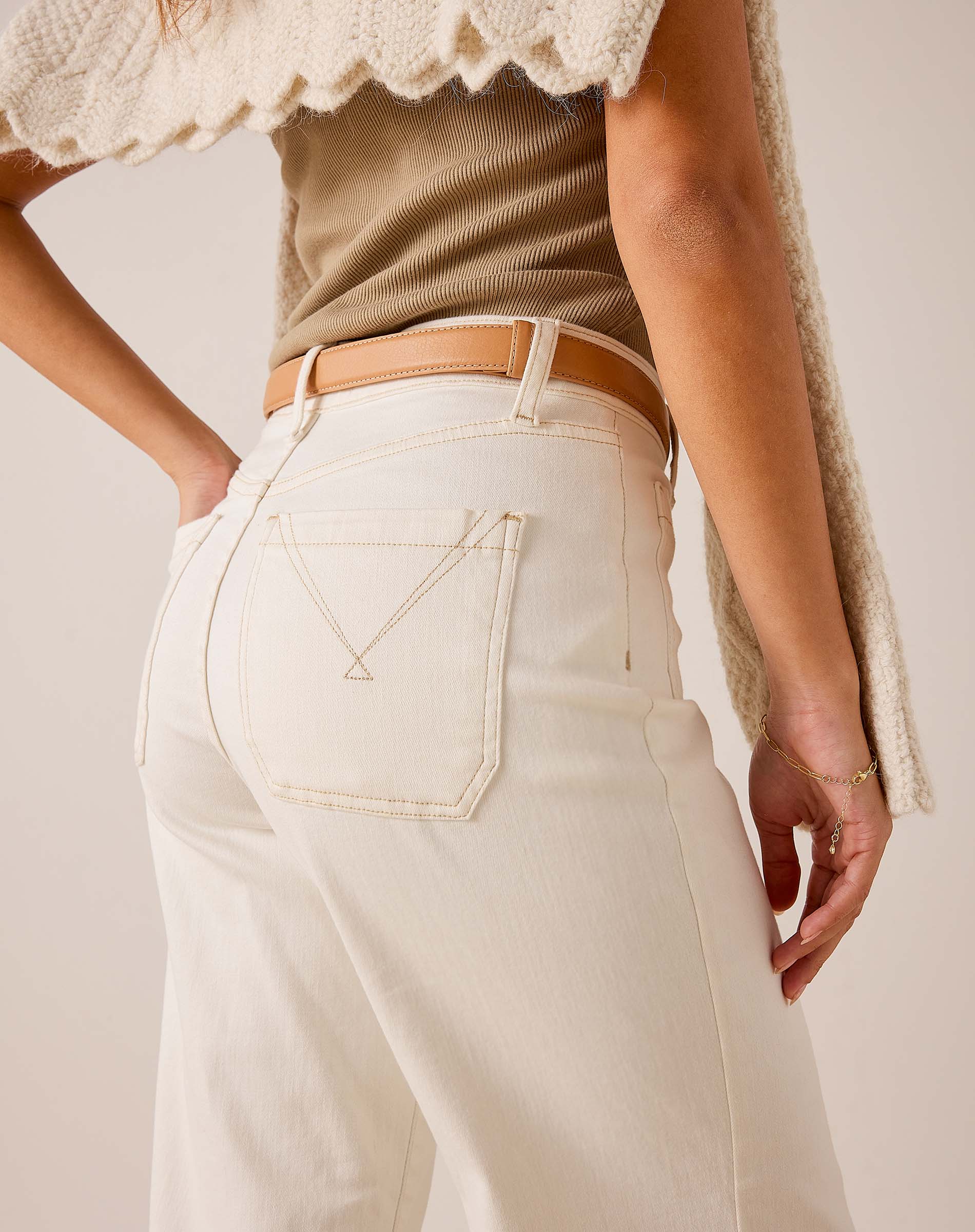 White wide-leg cropped trousers in a structured cotton blend with a decorative back pocket and tan leather belt.