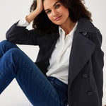 female wearing navy twill peacoat over a white collared shirt sitting on a white background