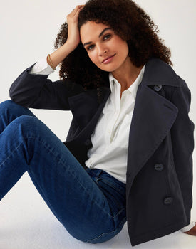 female wearing navy twill peacoat over a white collared shirt sitting on a white background