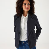 female wearing navy twill peacoat over a white collared shirt with blue jeans on a white background