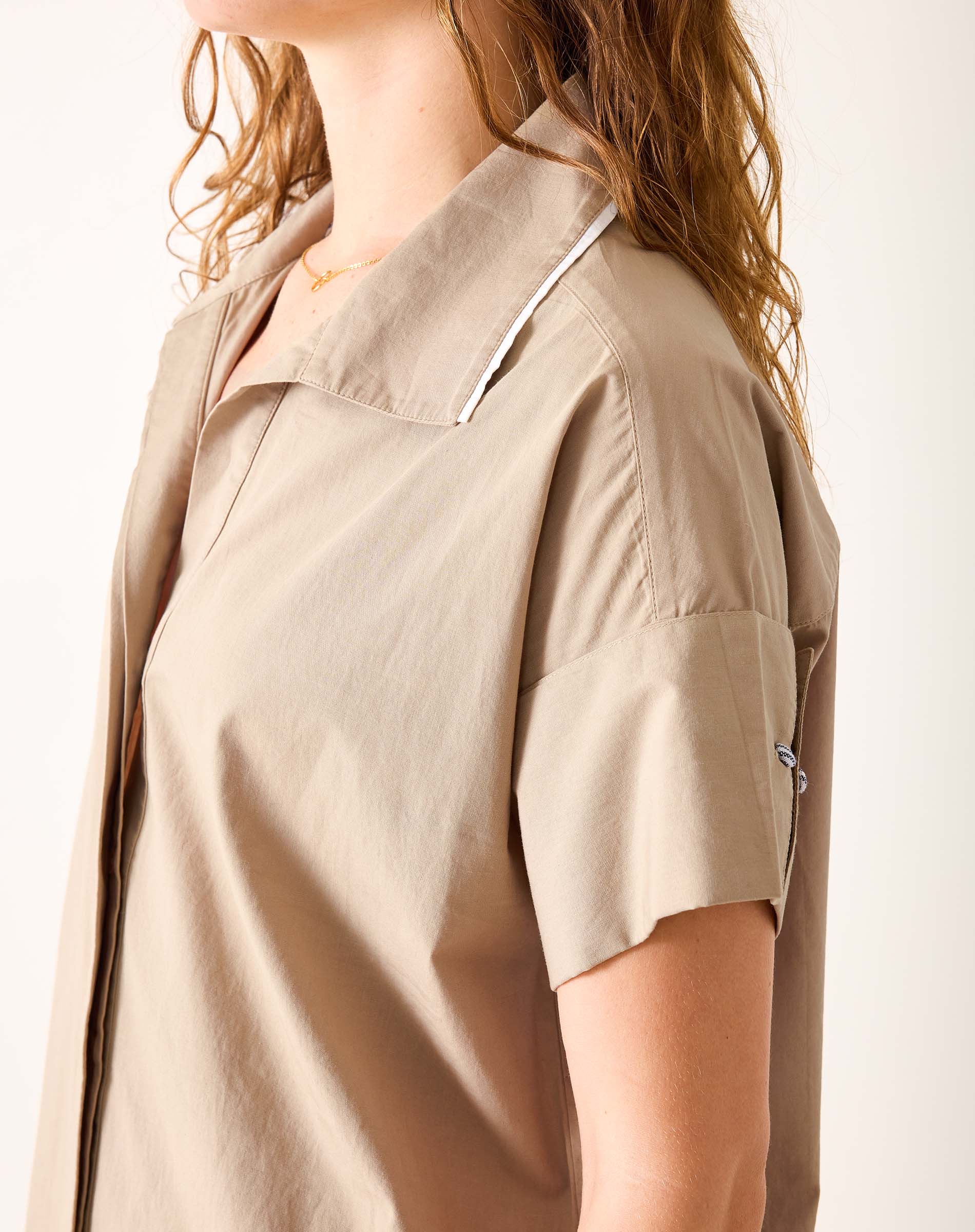 Model wearing a khaki-colored sailor wide hem dress with a unique layered collar and short sleeves.