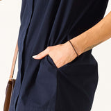 Model wearing a navy blue wide-hem dress with a side pocket.